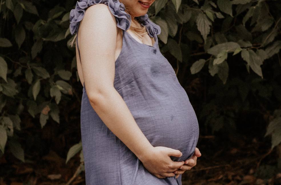 A woman in a blue dress enjoying nature during pregnancy