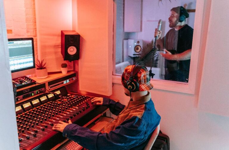 Australia bans AI-generated songs from official music charts Two men engaged in a vocal recording session in a modern music studio, highlighting sound equipment