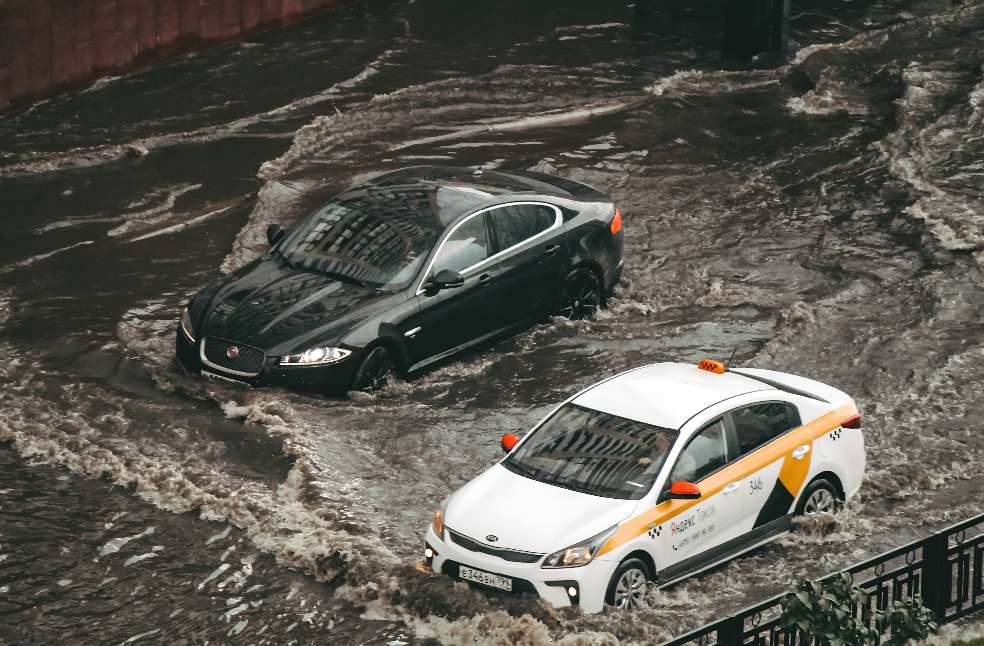 Cars navigating through a flooded city street, showcasing urban chaos and weather impacts