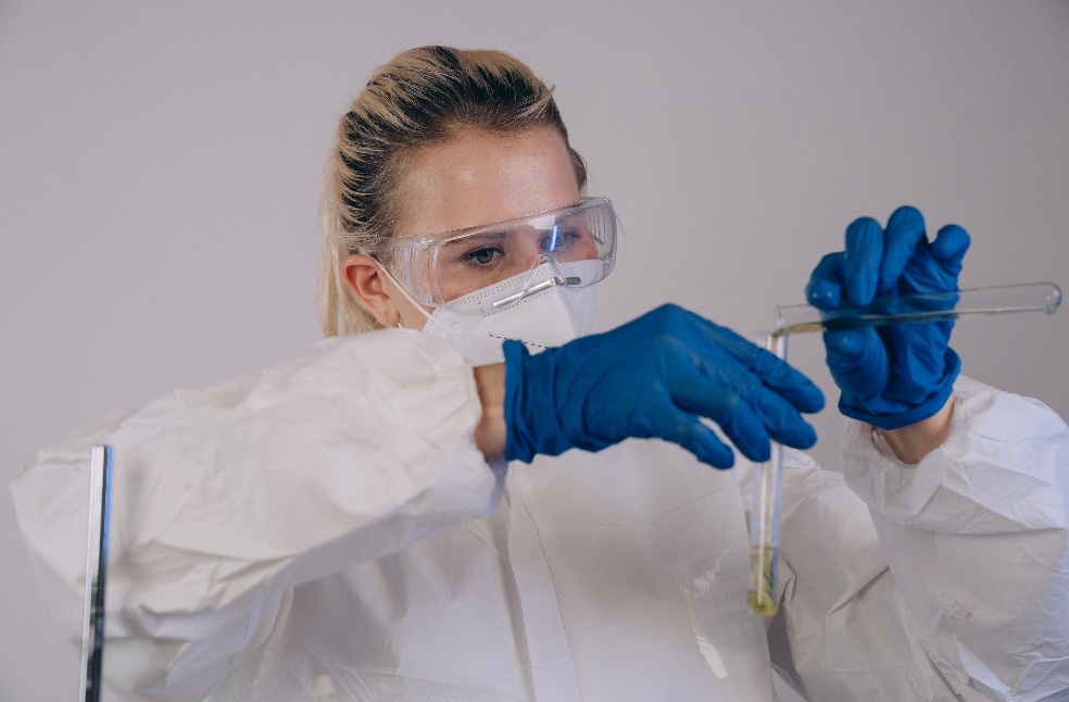 Scientist wearing PPE conducts laboratory experiment using test tubes