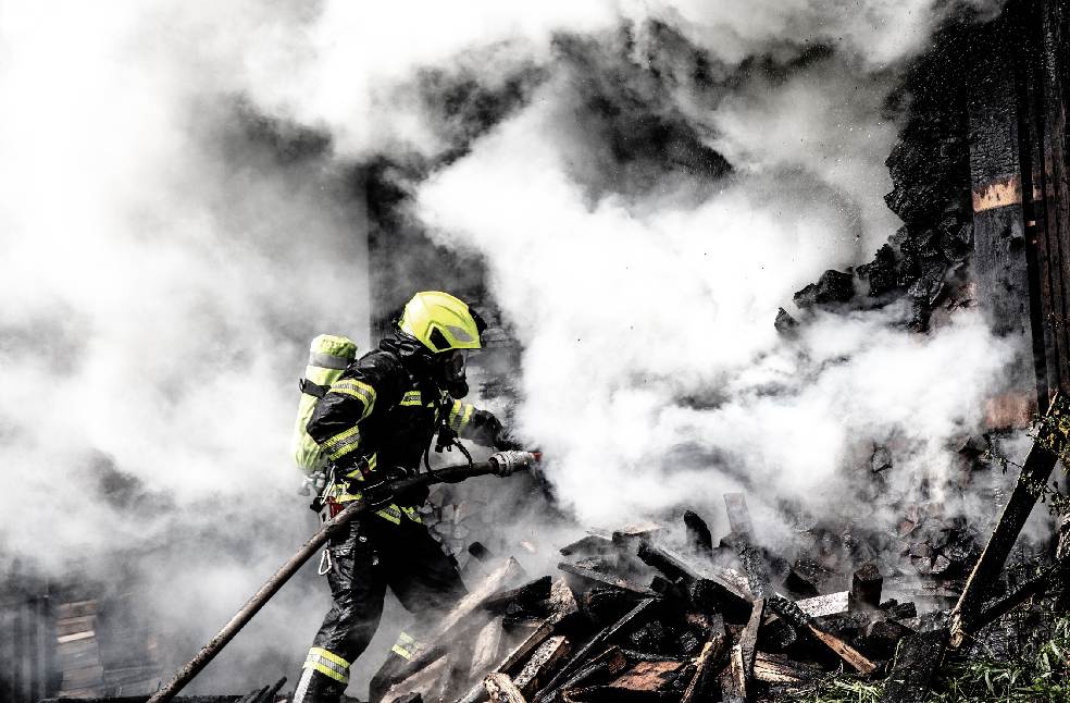 A determined firefighter fights a raging fire amidst thick smoke, highlighting bravery and courage