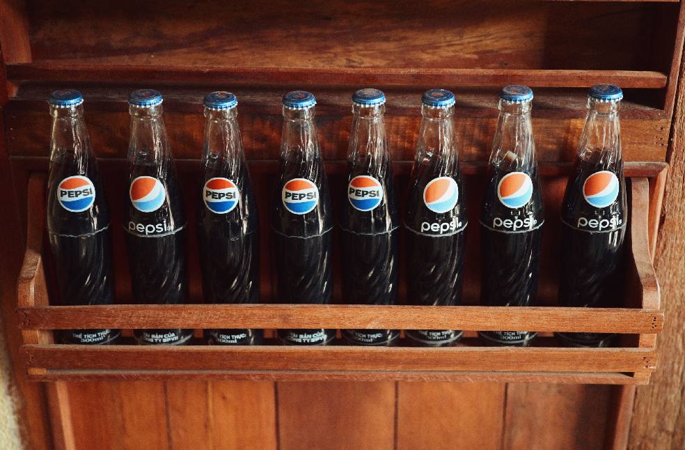 A collection of vintage Pepsi bottles showcased in a rustic wooden rack.