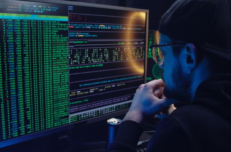 North Korea hackers use AI to boost cyberattack tactics Man intently working on computer programming with code displayed on dual monitors in a dimly lit room