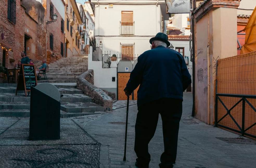 A candid view of an elderly man with a cane strollin