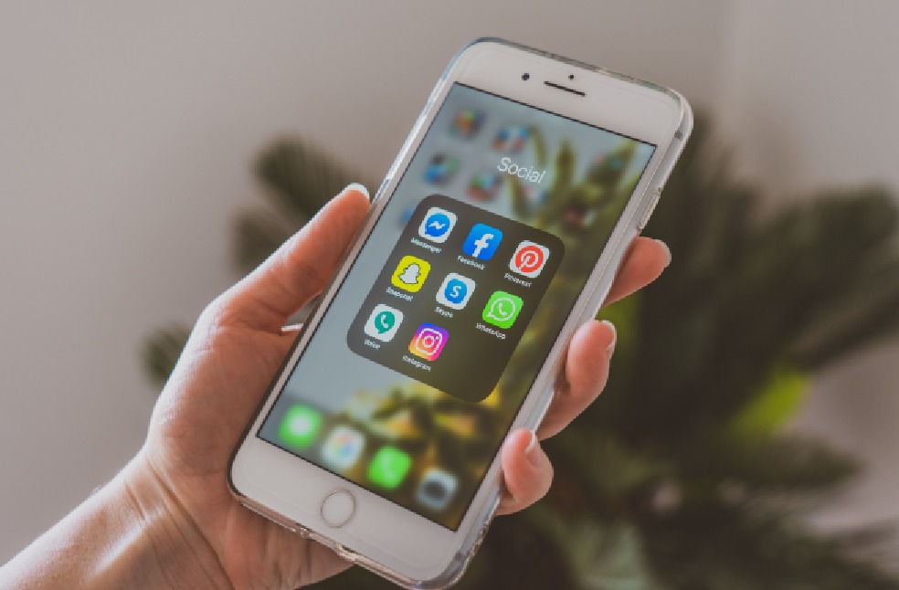Close-up of a hand holding a smartphone displaying popular social media apps