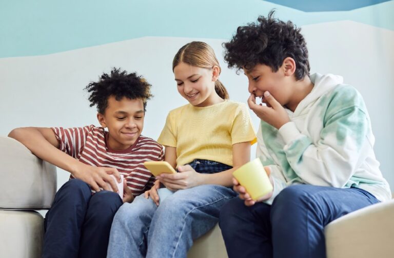 New Zealand proposes social media ban for children under 16 Three teenagers are enjoying each other's company while using smartphones indoors