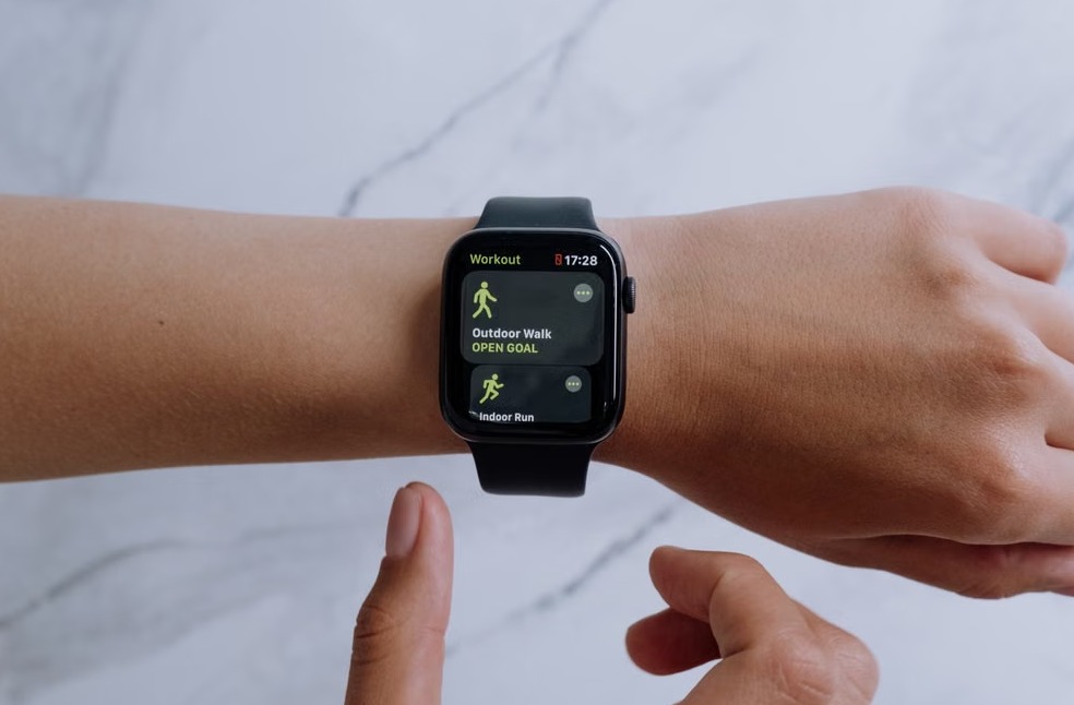 Close-up of a smartwatch on a wrist displaying health and fitness apps with a marble background