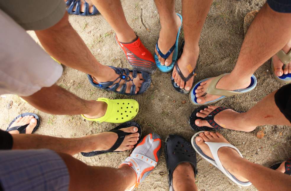 Group of friends enjoying summer by the beach, wearing colorful flip flops