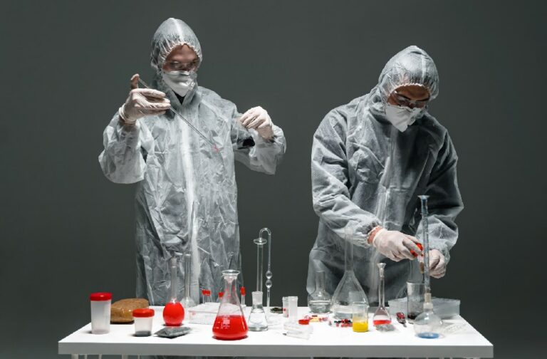 Study reveals fridge free vaccines may improve global access Two scientists in protective gear conducting experiments with lab equipment.