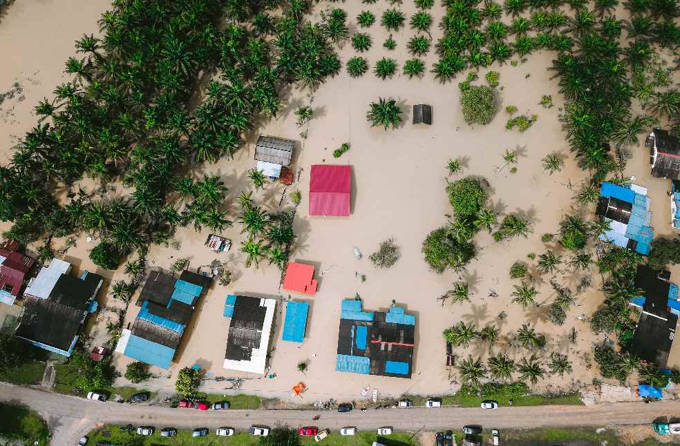 Aerial view of a flooded village in Kijal, Malaysia, surrounded by palm trees, illustrating the natural disaster's impact