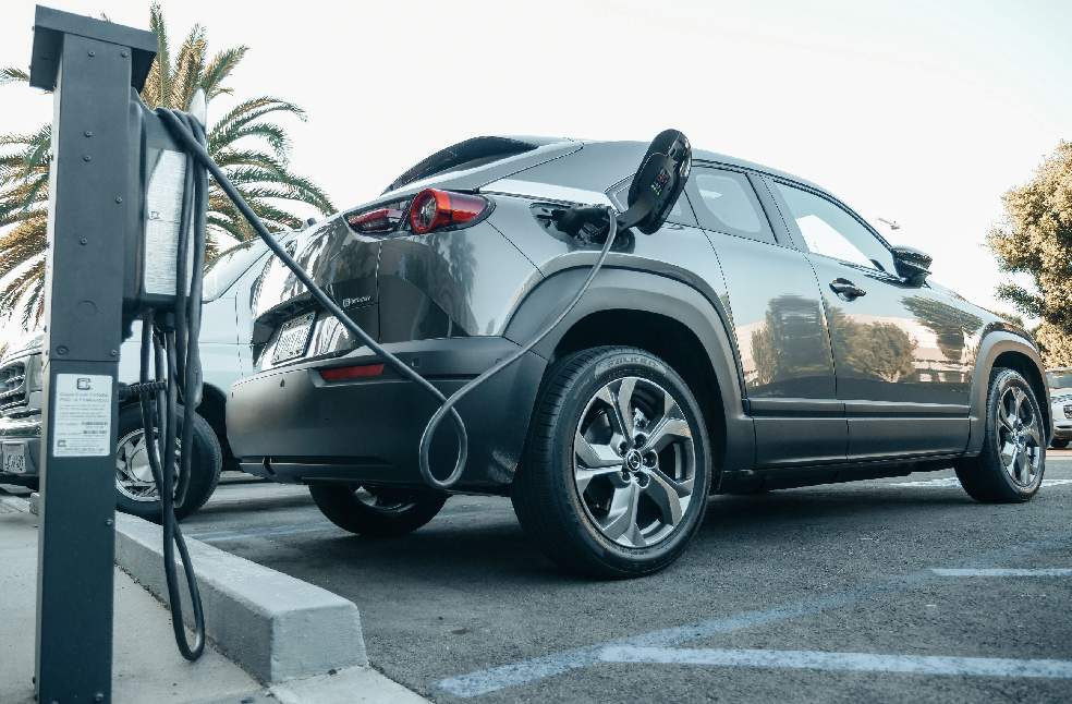 Modern electric vehicle charging at an outdoor station in daylight.