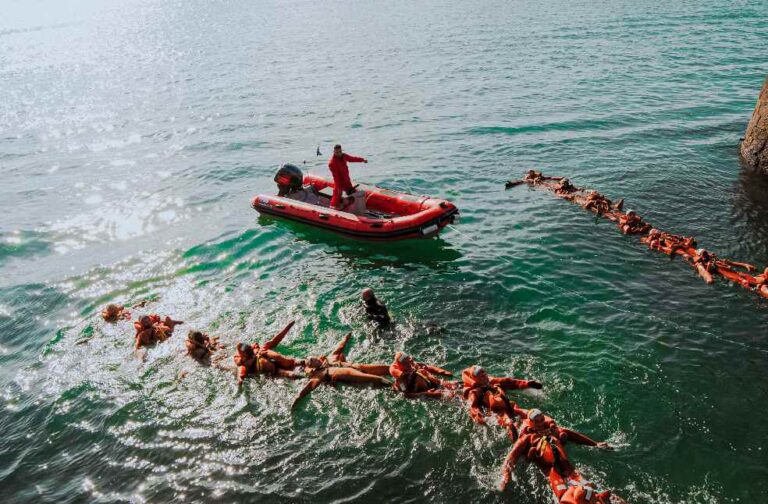 Indonesia ferry disaster leaves 26 dead, 109 still missing Aerial view of lifeguards in orange gear practicing rescue drills in the ocean.