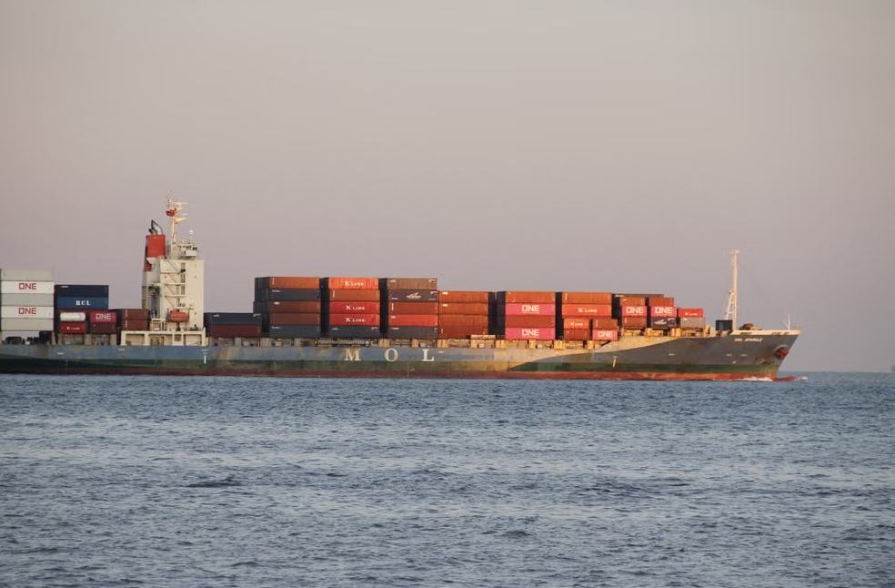 A large container ship carrying numerous shipping containers sails