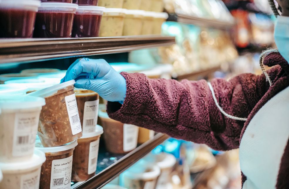 A masked woman selects packaged food in a grocery store during the pandemic