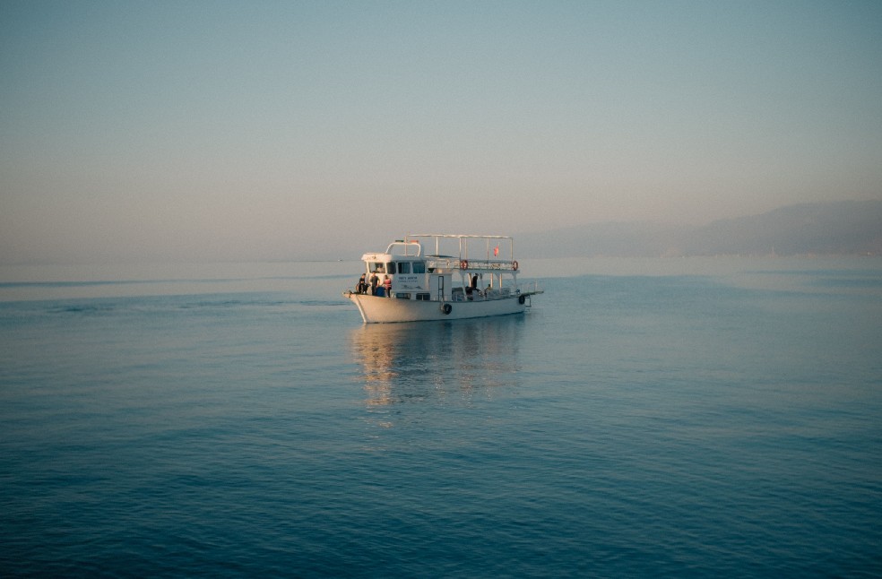 A tranquil scene of a boat gliding on calm ocean waters during sunrise, evoking peace and serenity