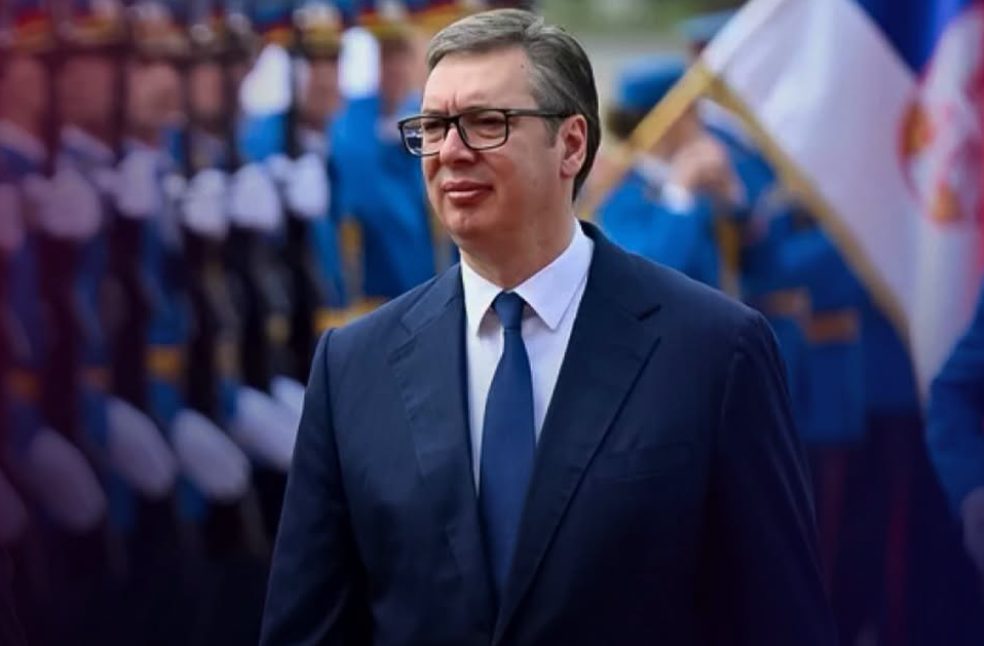Serbian President Aleksandar Vucic wearing glasses and a suit walking past an honor guard