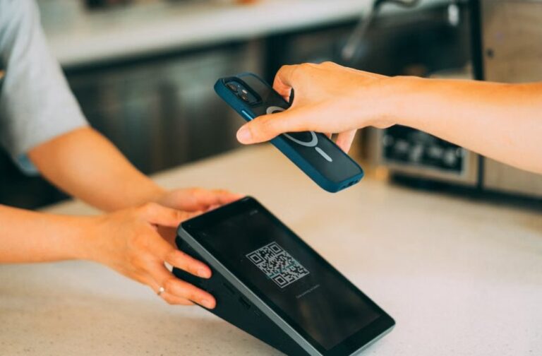 India prepares UPI rollout for AI-powered agentic payments Close-up of a contactless payment using a smartphone and QR code scanner in a modern retail setting