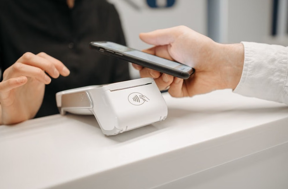 Person using a smartphone for contactless payment at a retail counter