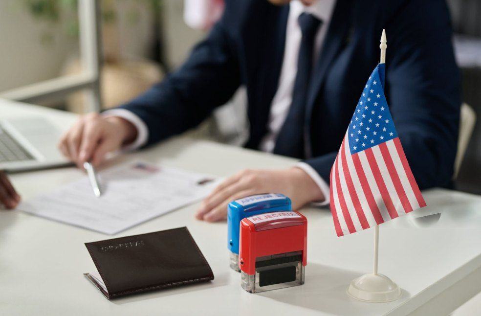 US immigration officer checking a visa application with the US flag displayed in the background