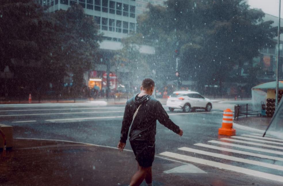 A man walks across a street crosswalk during a rainy day in the city