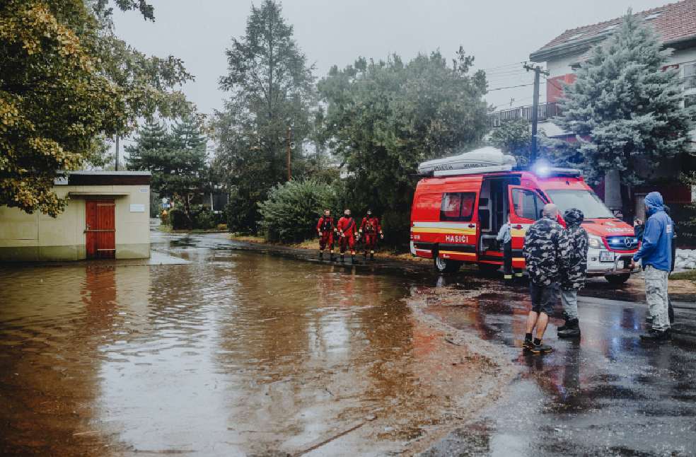 Emergency personnel managing flood with rescue vehicle. Urban scene with standing water.