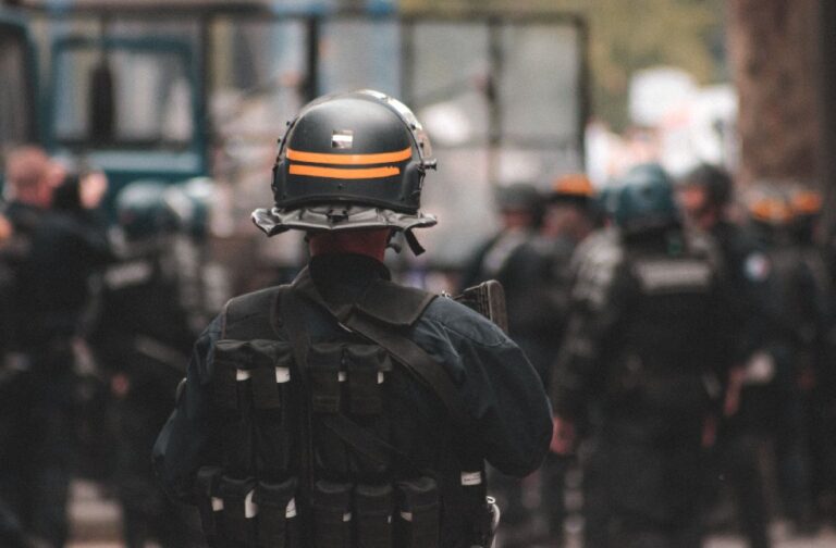 Germany, France prepare for Halloween protest weekend Police officer in full riot gear with blurred background of officers in action during daytime patrol.