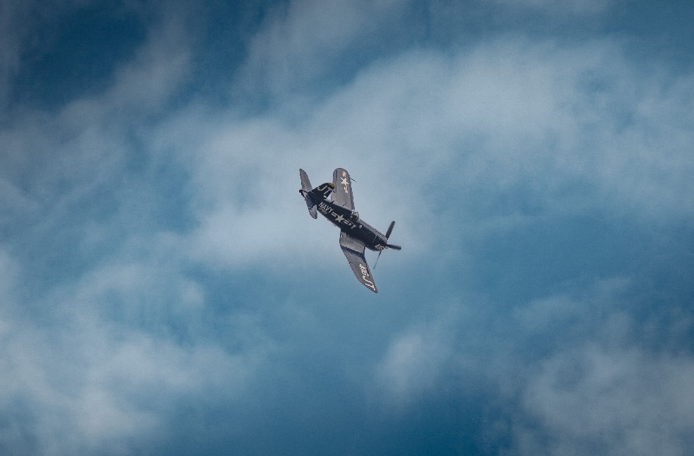 A historic fighter plane gracefully soars through the clouds, showcasing aviation's legacy.