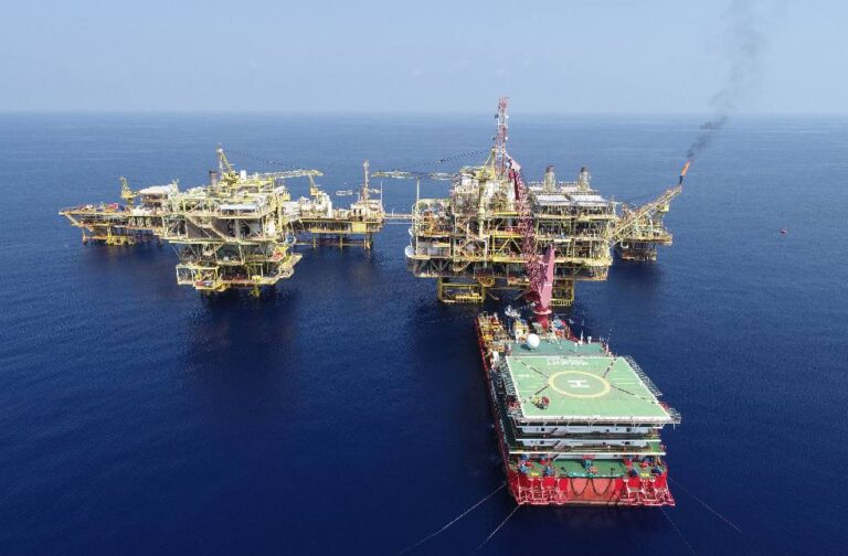 Asian markets decline while oil climbs ahead of key AI results Aerial shot of multiple offshore oil platforms in a serene, blue sea under clear skies.