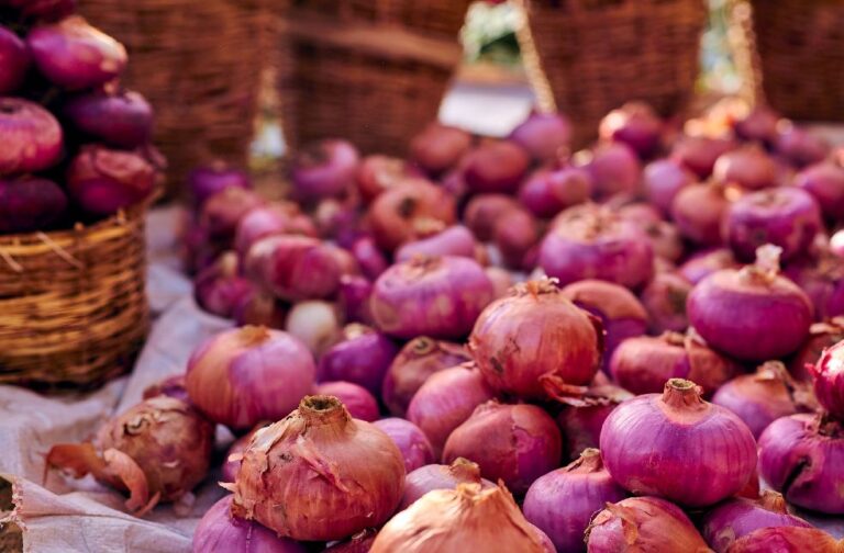 Philippines imposes record fine over onion price crisis Vibrant display of red onions in wicker baskets at an outdoor market.