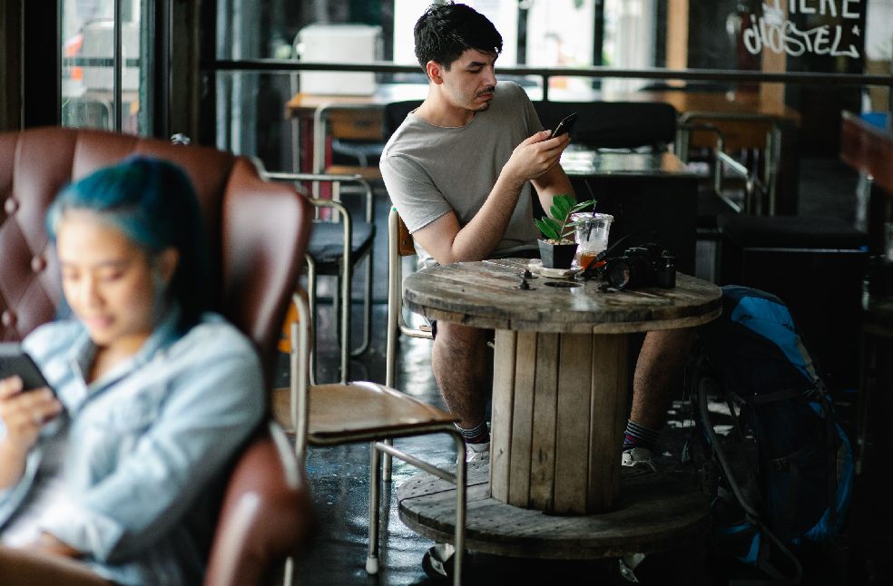 Young adults using smartphones in a cozy café, capturing the modern lifestyle and connectivity indoors.