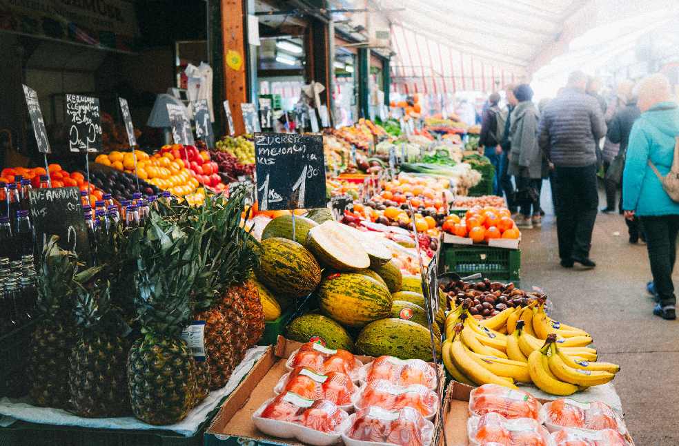 Colorful fruits and vegetables on display at a bustling outdoor market in Vienna, Austria.